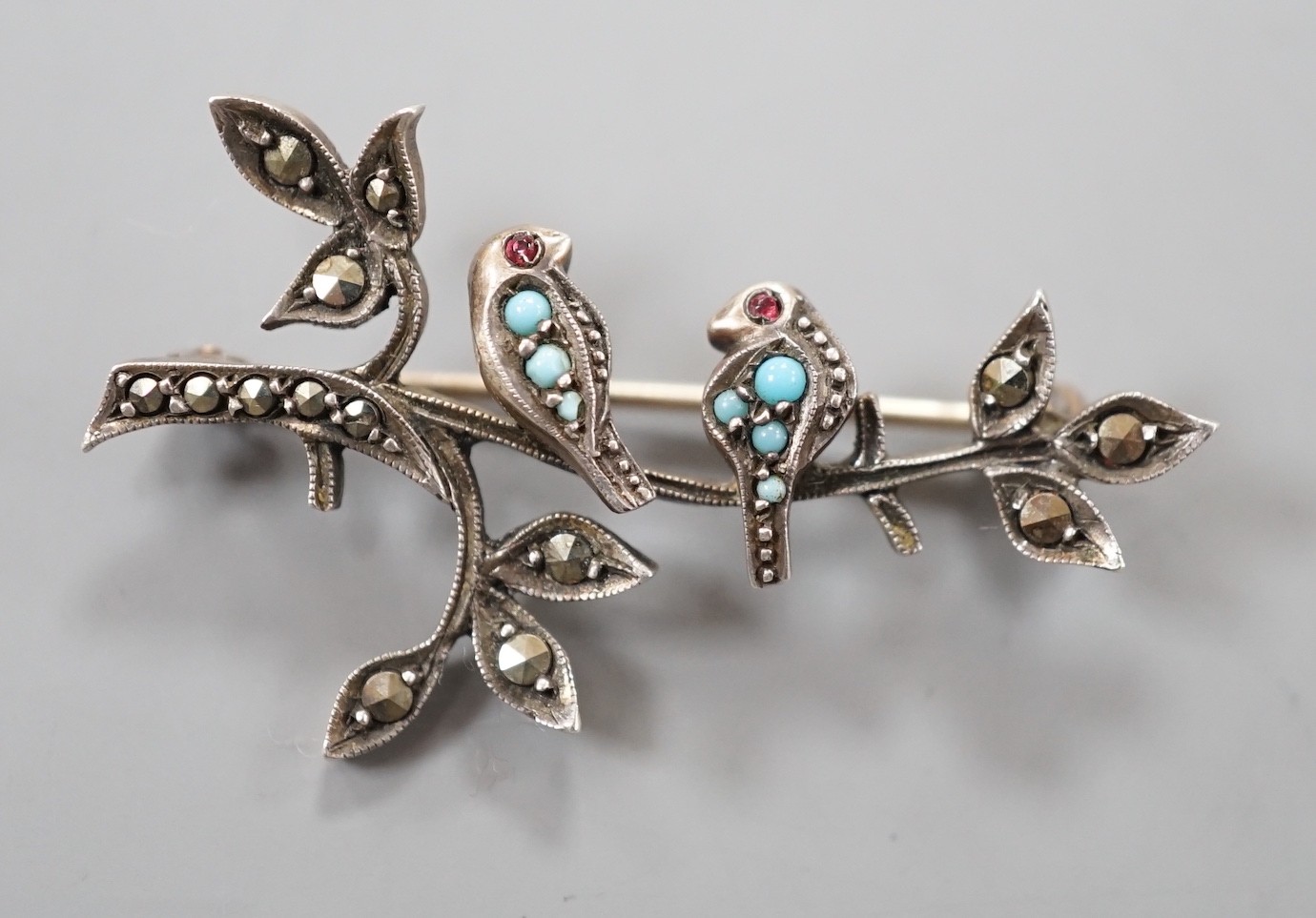 An early 20th century, yellow and white metal, turquois and marcasite set bar brooch, modelled as two birds on a branch, 39mm.